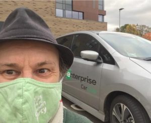 Councillor Ben in a mask by a rental car